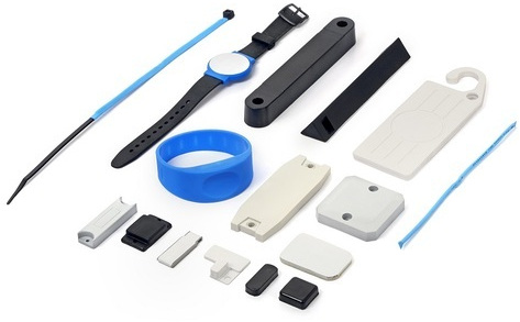 An assortment of UHF RFID tags laid out together: wristbands, cable ties, hard tags, laundry tags and adhesive labels